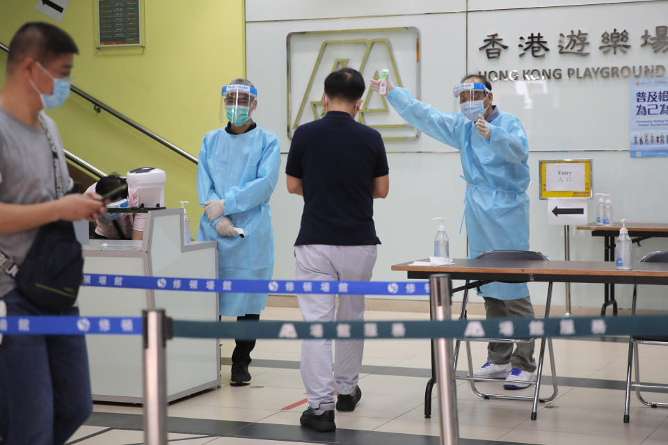 People receive temperature check at a coronavirus testing center in Hong Kong, Tuesday, Sept. 1, 2020. Hong Kong began a voluntary mass-testing program for coronavirus Tuesday as part of a strategy to break the chain of transmission in the city's third outbreak of the disease. The virus-testing program has become a flash point of political debate in Hong Kong, with many distrustful over resources and staff being provided by the China's central government and fears that the residents’ DNA could be collected during the exercise (AP Photo/Kin Cheung)