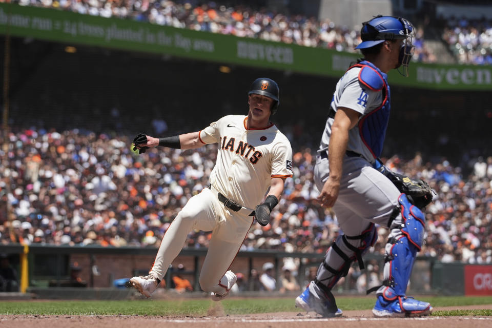 San Francisco Giants' Tyler Fitzgerald, left, scores next to Los Angeles Dodgers catcher Austin Barnes on Austin Slater's sacrifice fly during the second inning of a baseball game Sunday, June 30, 2024, in San Francisco. (AP Photo/Godofredo A. Vásquez)