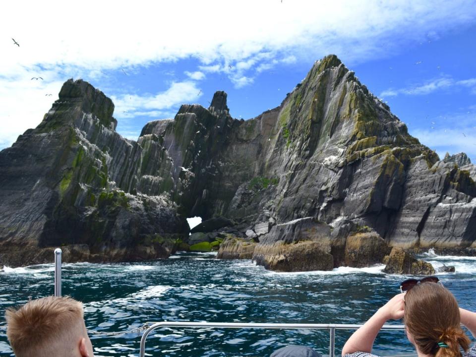 people taking pictures of skelling michael from a boat on the ocean