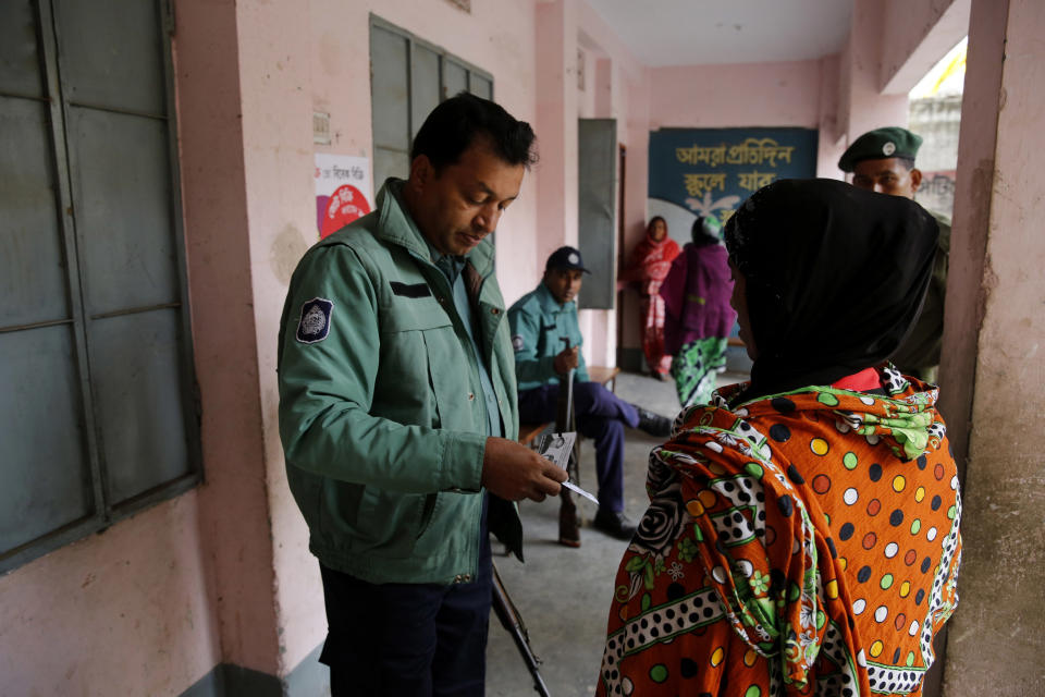 A Bangladeshi policeman checks the election card of a woman outside a polling station, in Dhaka, Bangladesh, Sunday, Jan. 5, 2014. Police in Bangladesh fired at protesters and more than 100 polling stations were torched in Sunday's general elections marred by violence and a boycott by the opposition, which dismissed the polls as a farce. (AP Photo/ Rajesh Kumar Singh)