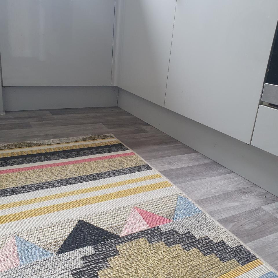 Amazon rug grippers applied to a patterned rug on top of a kitchen lino flooring