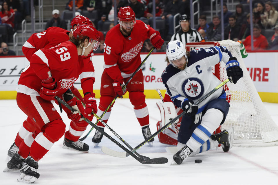 Winnipeg Jets right wing Blake Wheeler (26) tries to control the puck as Detroit Red Wings left wing Tyler Bertuzzi (59) and Mike Green (25) defend in the first period of an NHL hockey game Thursday, Dec. 12, 2019, in Detroit. (AP Photo/Paul Sancya)