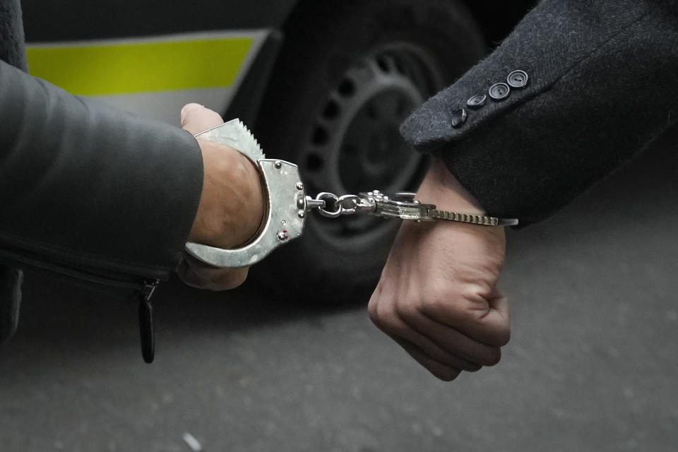 Police officers escort Andrew Tate, left, handcuffed to his brother Tristan, outside the Directorate for Investigating Organized Crime and Terrorism (DIICOT) where prosecutors examine electronic equipment confiscated during the investigation in their case, in Bucharest, Romania, Thursday, Jan. 26, 2023. Divisive influencer Andrew Tate and his brother Tristan, are held on charges of being part of an organized crime group, human trafficking and rape. (AP Photo/Vadim Ghirda)