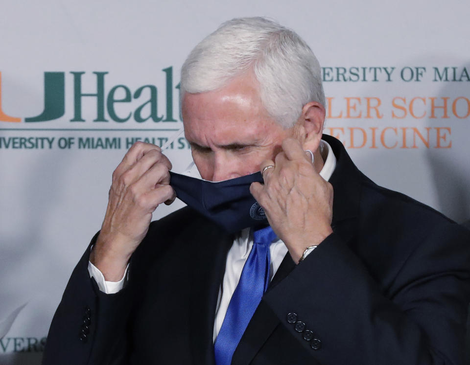 Vice President Mike Pence takes off his mask before speaking during a news conference at the University of Miami Miller School of Medicine Don Soffer Clinical Research Center, Monday, July 27, 2020, in Miami. Pence was in Florida to mark the beginning of Phase III trials for a coronavirus vaccine. (AP Photo/Wilfredo Lee)