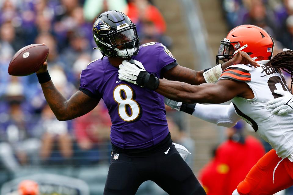 Baltimore Ravens quarterback Lamar Jackson (8) gets set to pass as Cleveland Browns defensive end Jadeveon Clowney (90) grabs him by the jersey during the first quarter of an NFL football game, Sunday, Oct. 23, 2022, in Baltimore. The Ravens defeated the Browns 23-20. (AP Photo/Rich Schultz)