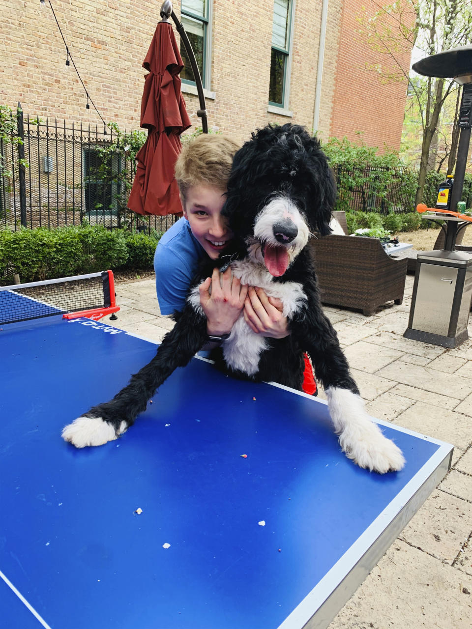 In this Saturday, May 2, 2020 photo provided by his family, Hudson Drutchas, 12, hugs his dog, Ty, outside his Chicago home. Hudson says his pets are helping get him through the pandemic. (Kristin Drutchas via AP)