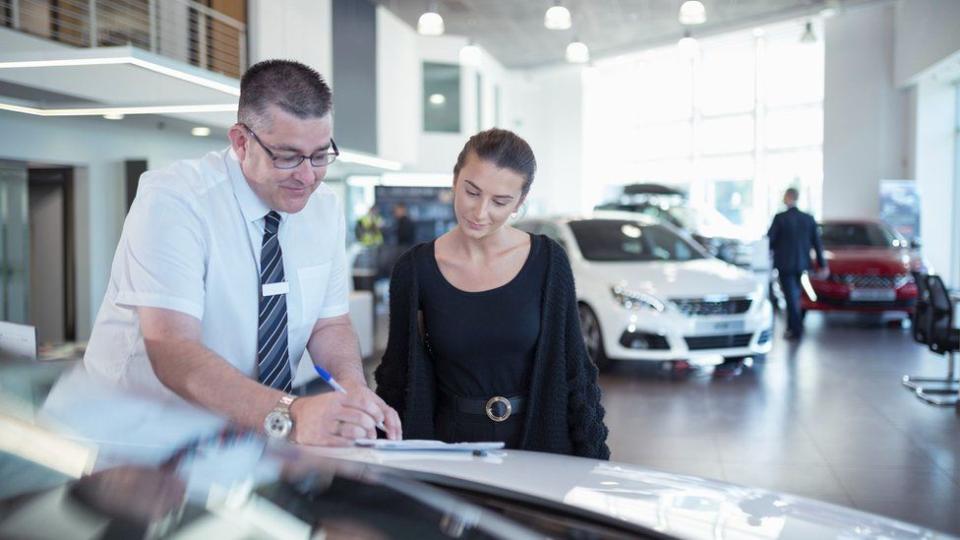 Una mujer y un vendedor en un salón de venta de automóviles