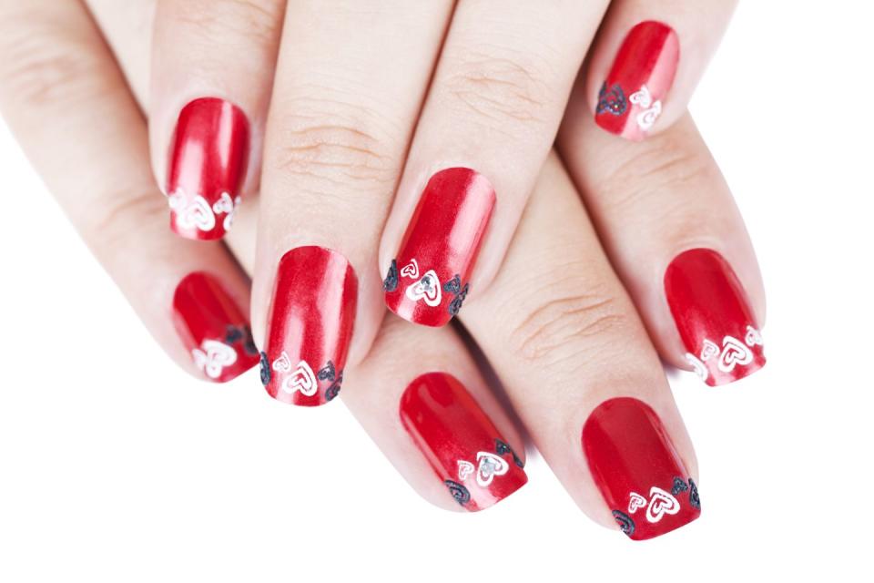 <p>Plan this look for an ultra-romantic date night. The ruby red nails have an element of fun with swirly red and black hearts and a few gems.</p>