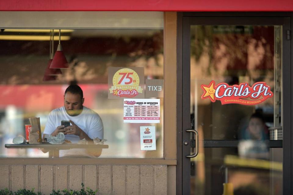 A customer sits in a Carl’s Jr. restaurant in this Fresno Bee file photo.