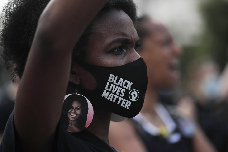 A woman wears earrings depicting First Lady Michelle Obama during a protest against racial injustice outside the White House from a section of 16th Street that's been renamed Black Lives Matter Plaza, Saturday, July 4, 2020, in Washington.(AP Photo/Maya Alleruzzo)