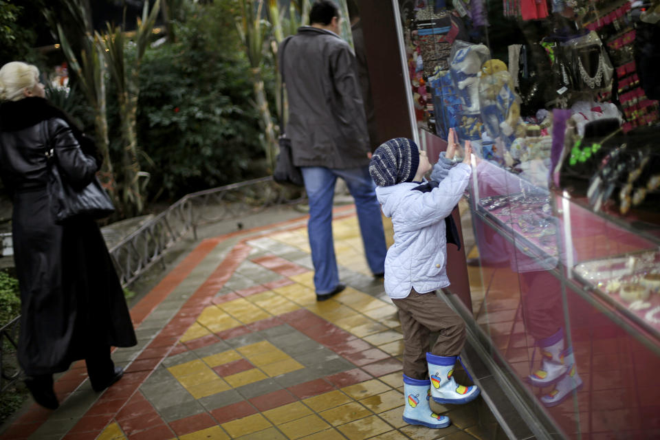 Leonid Gladko, 4, climbs up to get a better view of a stuffed animal in a store window, Wednesday, Jan. 29, 2014, in Sochi, Russia, home of the upcoming 2014 Winter Olympics. (AP Photo/David Goldman)