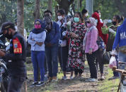 People watch from afar during the burial of a family member who presumably died of COVID-19 at a cemetery in Jakarta, Indonesia Friday, June 12, 2020. As Indonesia’s virus death toll rises, the world’s most populous Muslim country finds itself at odds with protocols put in place by the government to handle the bodies of victims of the pandemic. This has led to increasing incidents of bodies being taken from hospitals, rejection of COVID-19 health and safety procedures, and what some experts say is a lack of communication from the government. (AP Photo/Achmad Ibrahim)