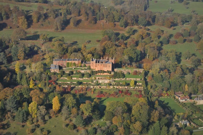 Overhead shot of Powis Castle, on a sptrawling property with well-maintained gardens, surrounded by fields and small wooded areas