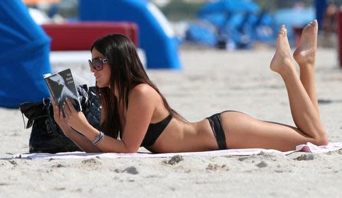 Model Claudia Romani had better be careful with that reading material! Photo by Corbis