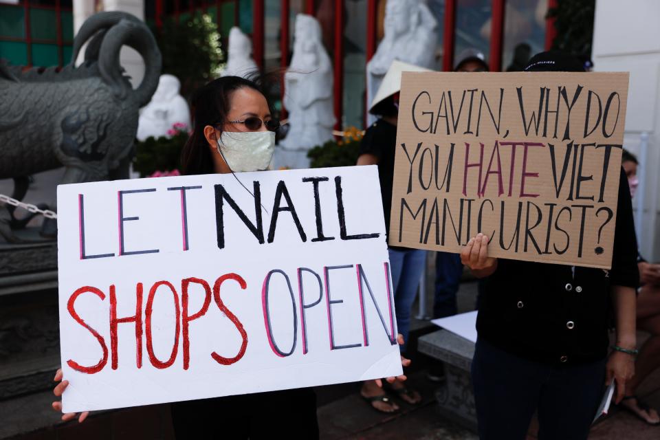 Nail salon workers hold signs during a protest in Westminster, Calif., on June 8 to demand Gov. Gavin Newsom lift COVID-19 restrictions on nail salons. The services can reopen starting June 19 in counties where health officials allow it.