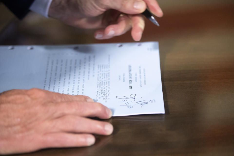 Nebraska Gov. Jim Pillen signs a copy of LB574, Monday, May 22, 2023, in Lincoln, Neb. Gov. Pillen signed a bill that bans abortion at 12 weeks of pregnancy and restricts gender-affirming medical care for people younger than 19. (Justin Wan/Lincoln Journal Star via AP)