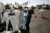 A group of volunteers put on protective suits at a city-run, drive-thru COVID-19 testing site in South Central Los Angeles, Friday, May 22, 2020. While most of California is welcoming a slight return toward normal this holiday weekend, Los Angeles will not be joining the party. The nation's largest county is not planning to reopen more widely until the next summer holiday, July 4th, because of a disproportionately large share of the state's coronavirus cases and deaths that have hampered the county's ability to rebound and meet strict criteria to get more people back to work. (AP Photo/Jae C. Hong)