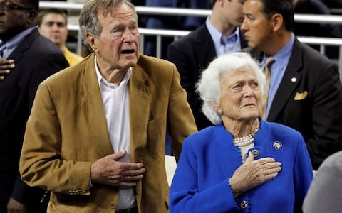 Former U.S. President George H.W. Bush and his wife, former first lady Barbara Bush, stand during the national anthem in Houston - Credit: Reuters