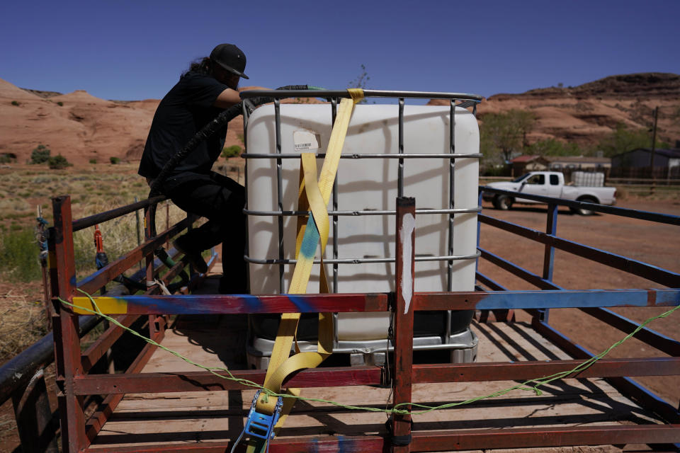 FILE - Chris Topher Chee waits for water to fill a tank in the back of his truck to haul home in Oljato-Monument Valley, Utah, on the Navajo reservation, April 27, 2020. The U.S. Federal Energy Regulatory Commission has rejected several proposed hydropower projects on the largest Native American reservation in the U.S. The commission has also created a policy that essentially gives tribes veto power over such projects early on. (AP Photo/Carolyn Kaster, File)