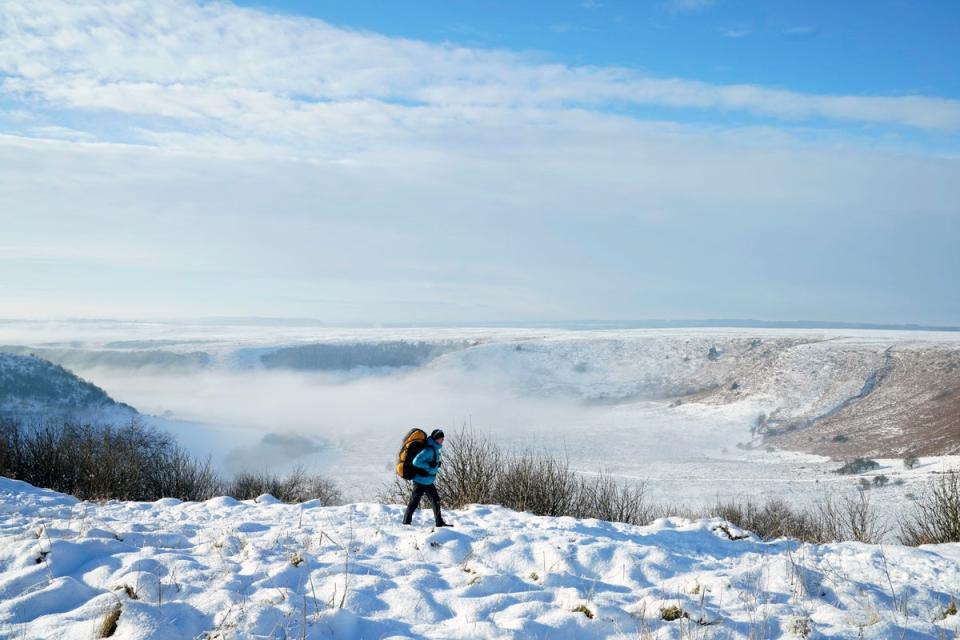 Walking through snow above the Hole of Horcum at the North York Moors National Park (PA)