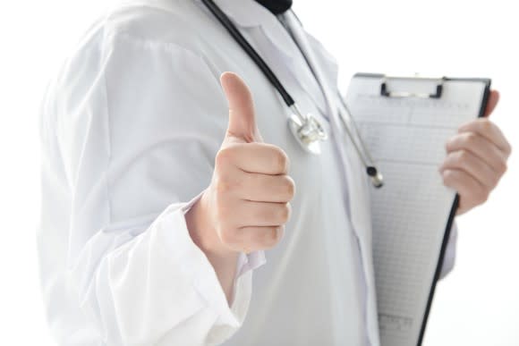 A physician holding a clipboard and giving the thumbs-up sign.