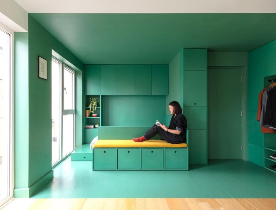 Homeowner Helen Zhou sitting in her studio apartment that she painted green.