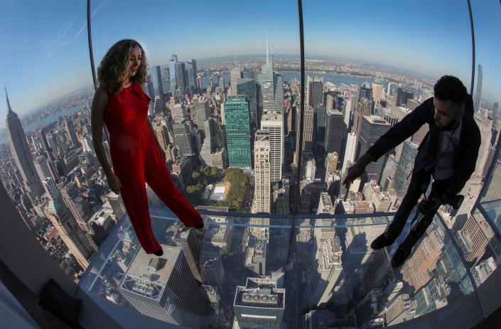 A woman poses for a photographer on one of the transparent floors above the New York City skyline during the official opening of the SUMMIT One Vanderbilt observation deck atop the new One Vanderbilt tower in Midtown Manhattan in New York City, New York, USA, 21 October, 2021. REUTERS/Mike Segar