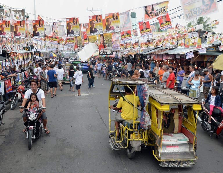 Motorists drive past election posters outside a polling station during mid-term elections in Manila, on May 13, 2013. People are going to the polls to choose thousands of local leaders plus national legislators in what is seen as a referendum on the presidency of reformist Benigno Aquino