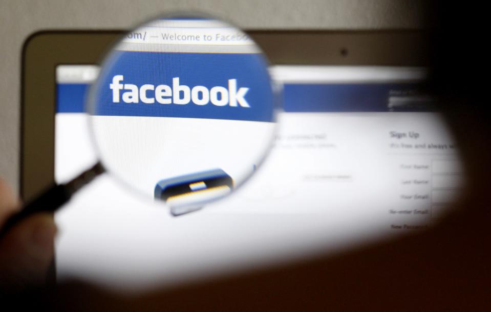 In this photo illustration, a Facebook logo on a computer screen is seen through a magnifying glass held by a woman in Bern