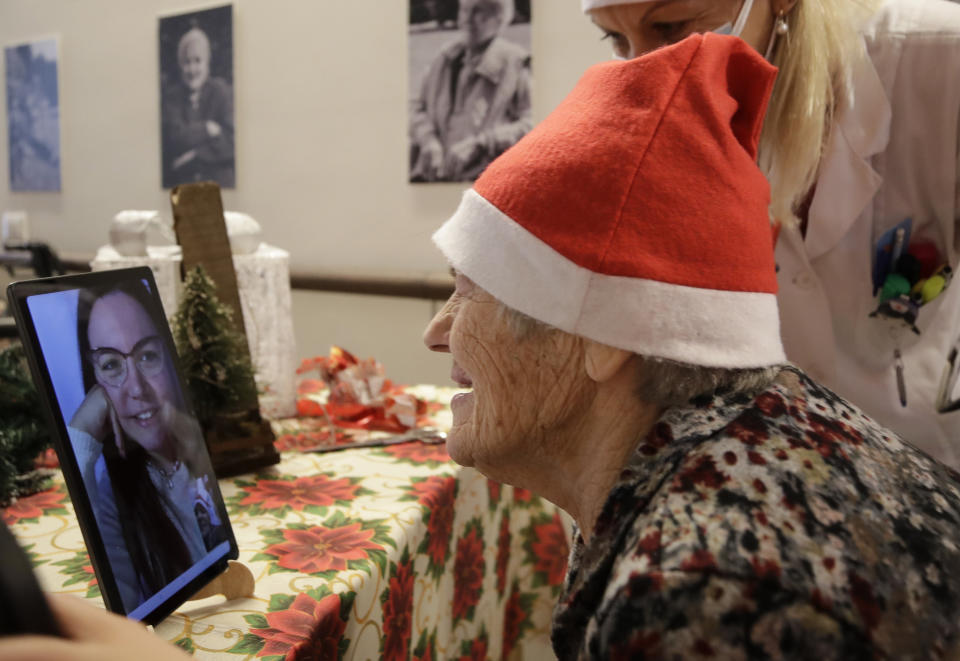 Caterina Bertocchi, 91, talks via video call with Irene Schiavone, a donor unrelated to her, who bought and sent her a Christmas present through an organization dubbed "Santa's Grandchildren", at the Martino Zanchi nursing home in Alzano Lombardo, one of the area that most suffered the first wave of COVID-19, in northern Italy, Saturday, Dec. 19, 2020. (AP Photo/Luca Bruno)