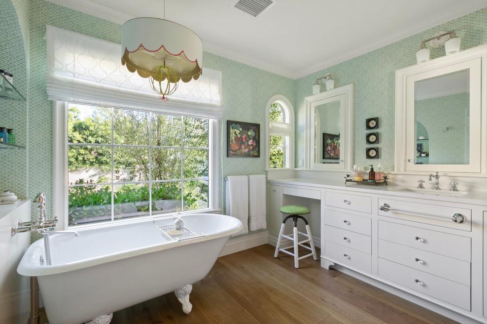 A bathroom with a large tub and green, patterned walls.