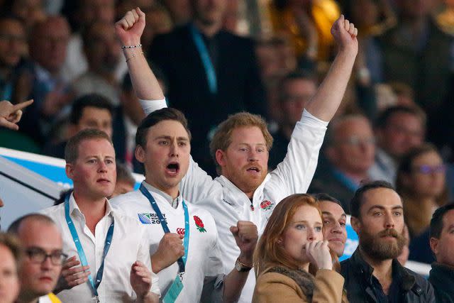 <p>Max Mumby/Indigo/Getty Images</p> Prince Harry with arms aloft watching England play rugby, with Charlie van Straubenzee at Twickenham, London on Oct. 3, 2015