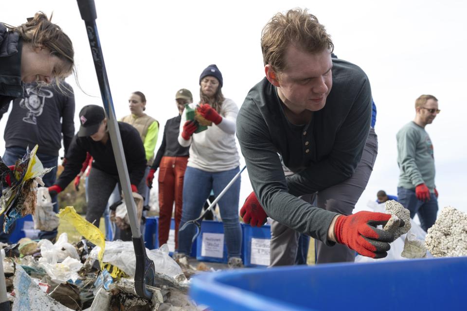 Volunteer Marc Gazda discards foam during a park cleanup on Wednesday, Nov. 15, 2023, at Anacostia Park in Washington. For decades, the Anacostia was treated as a municipal dumping ground for industrial waste, storm sewers and trash. A sewer upgrade in the city and decades of local environmental advocacy have brought improvements to the river, but change has come slowly. (AP Photo/Tom Brenner)