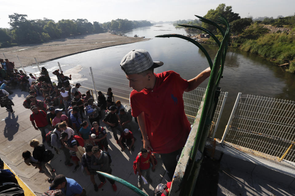 A migrant climbs the fence at the border crossing between Guatemala and Mexico in Tecun Uman, Guatemala, Saturday, Jan. 18, 2020. More than a thousand Central American migrants surged onto the bridge spanning the Suchiate River, that marks the border between both countries, as Mexican National Guardsmen attempted to impede their journey north. (AP Photo/Marco Ugarte)