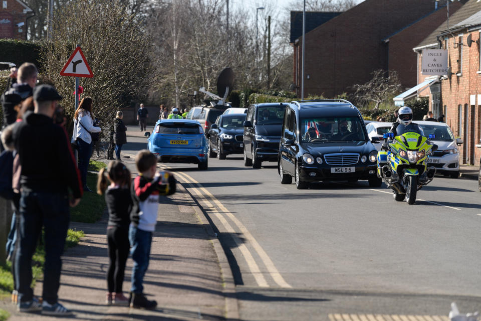 BEDFORD, ENGLAND - FEBRUARY 27: The funeral procession for Sir Tom Moore passes through the village of Marston Moretaine on the way to Bedford Crematorium ahead of a private ceremony on February 27, 2021 in Bedford, England. WWII veteran, Sir Tom raised nearly £33 million for NHS charities ahead of his 100th birthday last year by walking laps of his garden in Marston Moretaine, Bedfordshire. He died on the 2nd of February after testing positive for COVID-19. (Photo by Leon Neal/Getty Images)