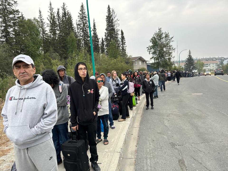 A line of people waiting at a high school in Yellowknife on Thursday morning, where they've been told to go to get on evacuation flights leaving the city starting at 1 p.m.