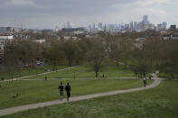 People jog down up Primrose Hill, with a backdrop of central London, as the lockdown due to the coronavirus outbreak continues in London, Tuesday, March 31, 2020. The British government advises people must try to stay at home to help stop the spread of coronavirus, they are allowed one form of exercise a day, such as a run, walk, or cycle, alone or with members of their household. The new coronavirus causes mild or moderate symptoms for most people, but for some, especially older adults and people with existing health problems, it can cause more severe illness or death. (AP Photo/Matt Dunham)
