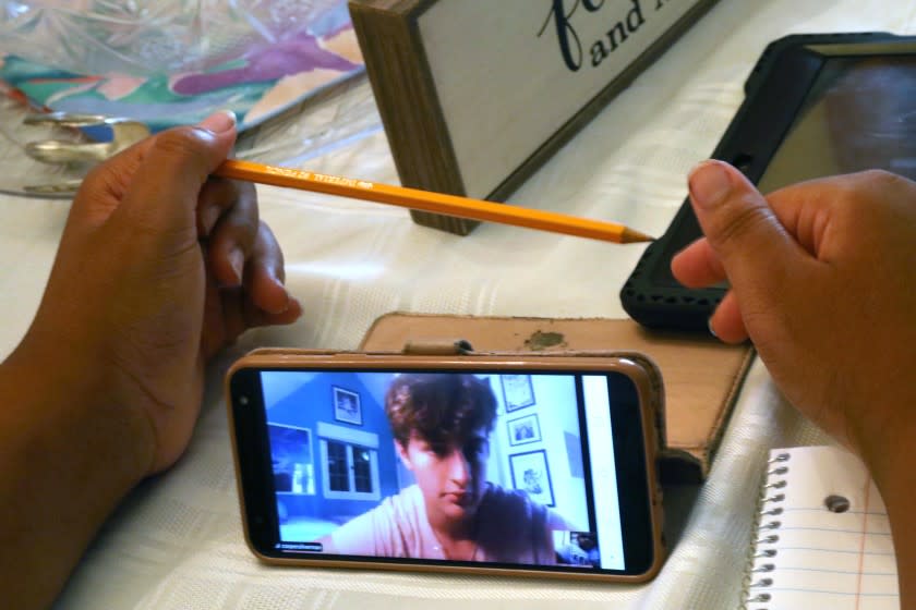 LOS ANGELES, CA - SEPTEMBER 08: 6th grade student Malachi Morris-Jackson, 11, holding pencil, is tutored for free by Cooper Silverman, a volunteer with El Nido Family Center, at Morris-Jackson's home in South Los Angeles on September 8, 2020. Morris-Jackson, a student at Orville Wright Middle School, was being tutored in math and English. As K-12 students fall behind in the face of the pandemic and e-learning, parents with means are scrambling to pair their kids with private one-on-one tutors. But the students who need this after-school support the most are the least likely to get it. Some organizations have stepped in to try to fill that void. Los Angeles on Tuesday, Sept. 8, 2020 Los Angeles, CA. (Genaro Molina / Los Angeles Times)