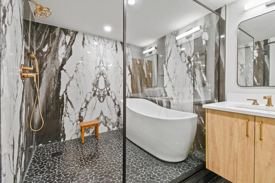 The primary bathroom has an oversize glassed-in “wet room” for the tub and shower. The walls are covered in book-matched porcelain.