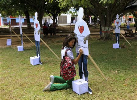 A student writes a message on a cut-out figure of an active rebel of the FARC during an event to campaign for FARC demobilisation in Tame, Arauca province, September 18, 2013. Colombia's Defence Minister Juan Carlos Pinzon and army chief commanders attended the event as part of the ongoing peace negotiation with FARC. REUTERS/Jose Miguel Gomez