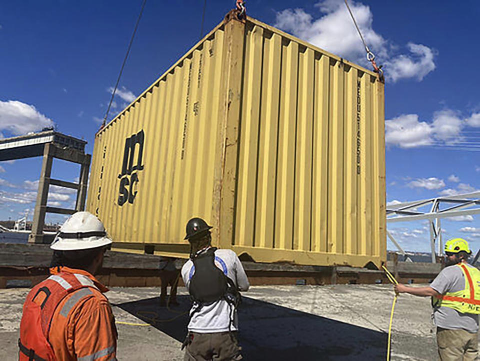 In this photo provided by the Key Bridge Response 2024 Unified Command, response crews begin removing shipping containers from the deck of the cargo ship Dali using a floating crane barge at the site of the Francis Scott Key Bridge, Sunday, April 7, 2024, in Baltimore. (Key Bridge Response 2024 Unified Command via AP)