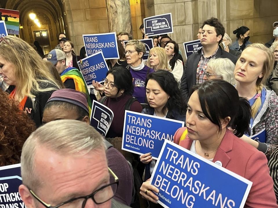 People hold signs protesting a bill that would ban gender-affirming medical procedures, including hormone therapy and surgical reassignment, for those 19 and younger, at the state Capitol on Wednesday, Feb. 8, 2023, in Lincoln, Neb. (AP Photo/Margery A. Beck)