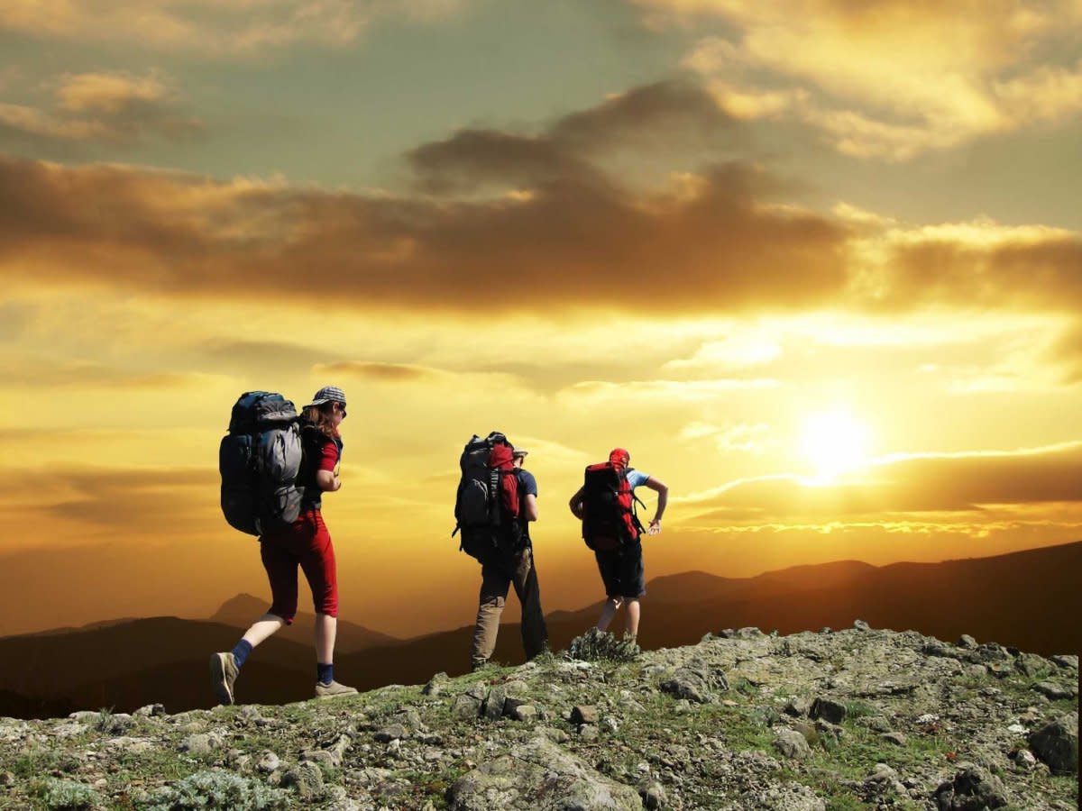 group hiking on hill sunset