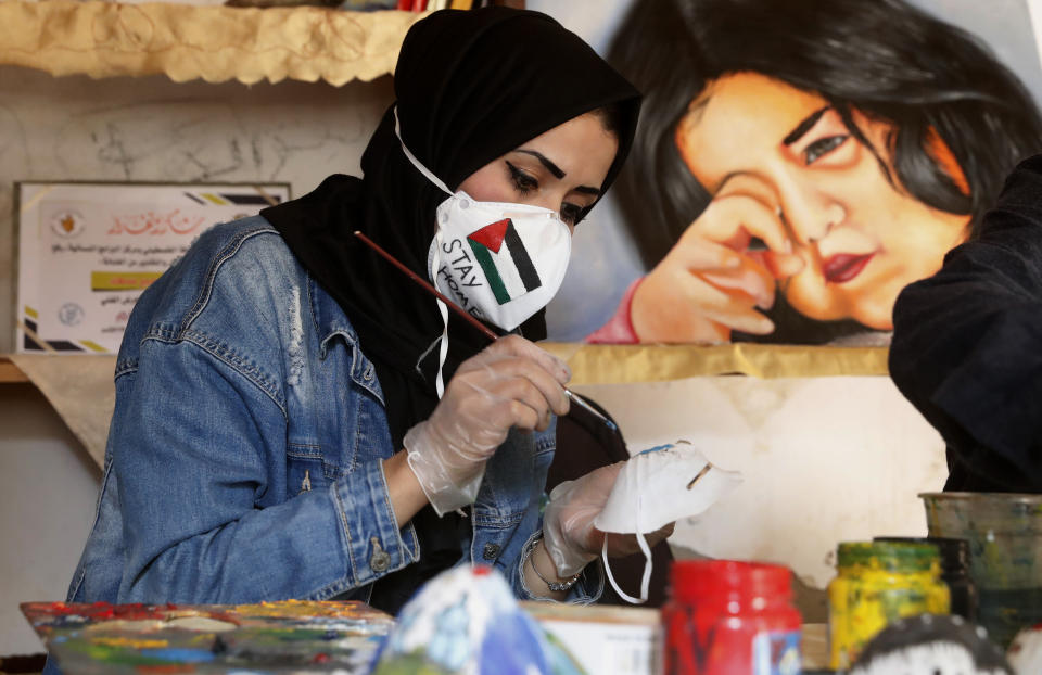 Palestinian artist Samah Saed, decorates a protective face mask to encourage people to wear them as a precaution against the coronavirus, at a workshop in the Shijaiyah neighborhood of Gaza, Thursday, April 2, 2020. (AP Photo/Adel Hana)