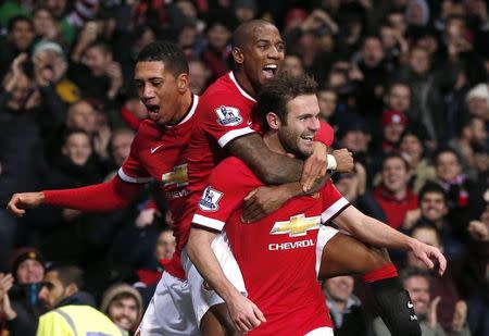 Manchester United's Juan Mata (R) celebrates with Ashley Young and Chris Smalling (L) after scoring his team's second goal during their English Premier League soccer match against Stoke City at Old Trafford in Manchester, northern England December 2, 2014. REUTERS/Phil Noble