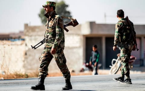 Syrian regime forces are pictured as they patrol a street on the western entrance of the town of Tal Tamr in the countryside of Syria's northeastern Hasakeh province on October 14, 2019 - Credit: AFP