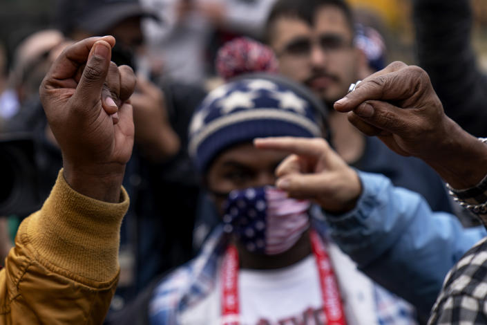 The hands of Biden supporter Angelo Austin, and Trump supporter C.L. Bryant, right, gesture as they argue while Trump supporters demonstrate against the election results outside the central counting board at the TCF Center in Detroit, Mich., Thursday, Nov. 5, 2020. (AP Photo/David Goldman)