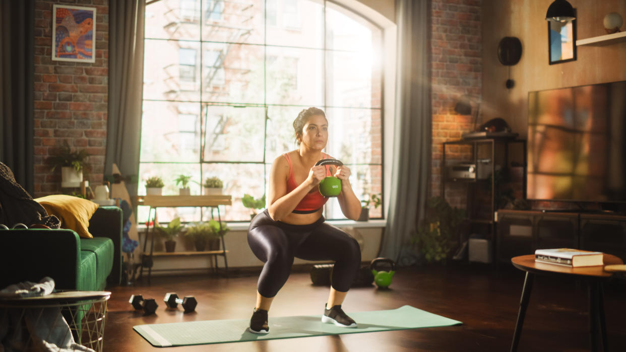  A woman doing a kettlebell workout at home. 