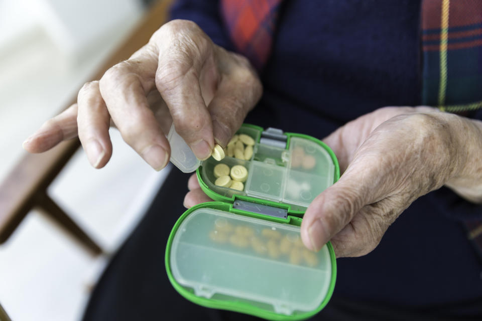 Elderly Turkish woman taking pills from green colored medicine box closeup view