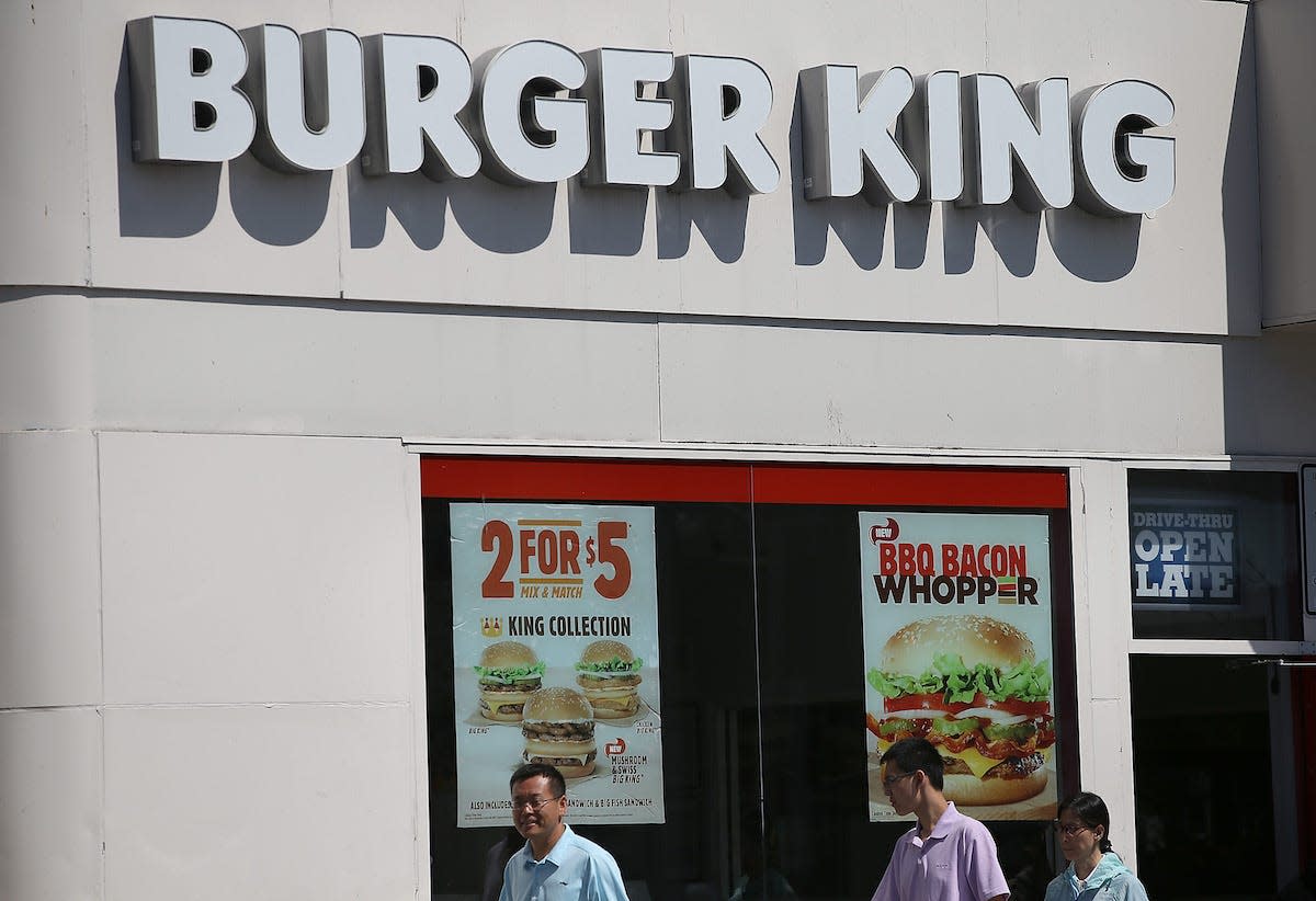 People walking past the front of a Burger King.